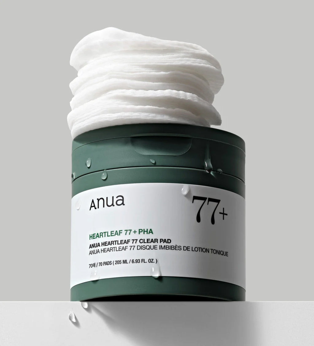 Anua Heartleaf 77 Clear Pad in grünem Behälter mit geöffnetem Deckel und Stapeln mit Toner getränkter Pads darauf.