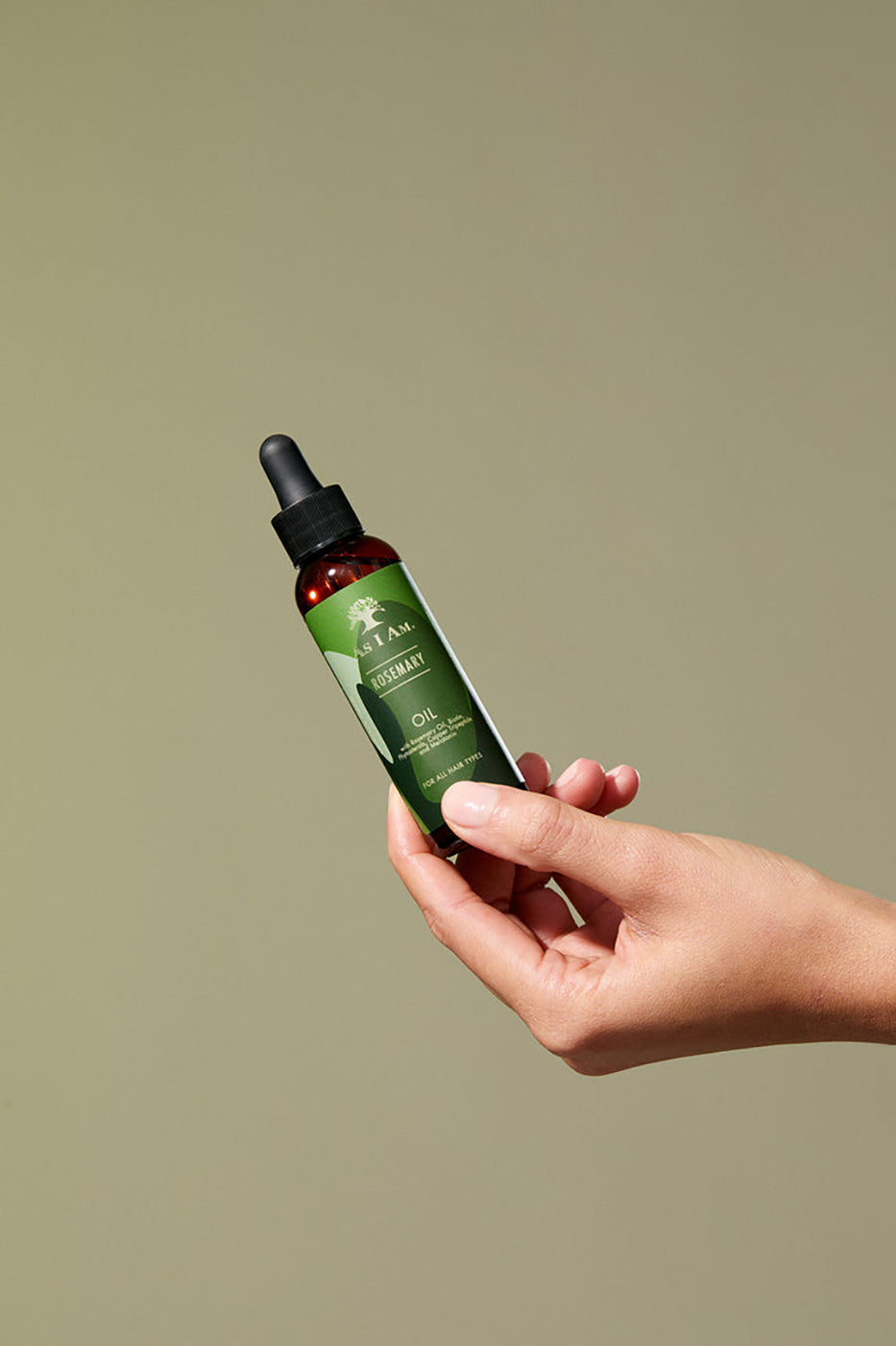 Eine Hand hält eine Flasche As I Am Rosmarinöl (60 ml) vor einem hellen Hintergrund.