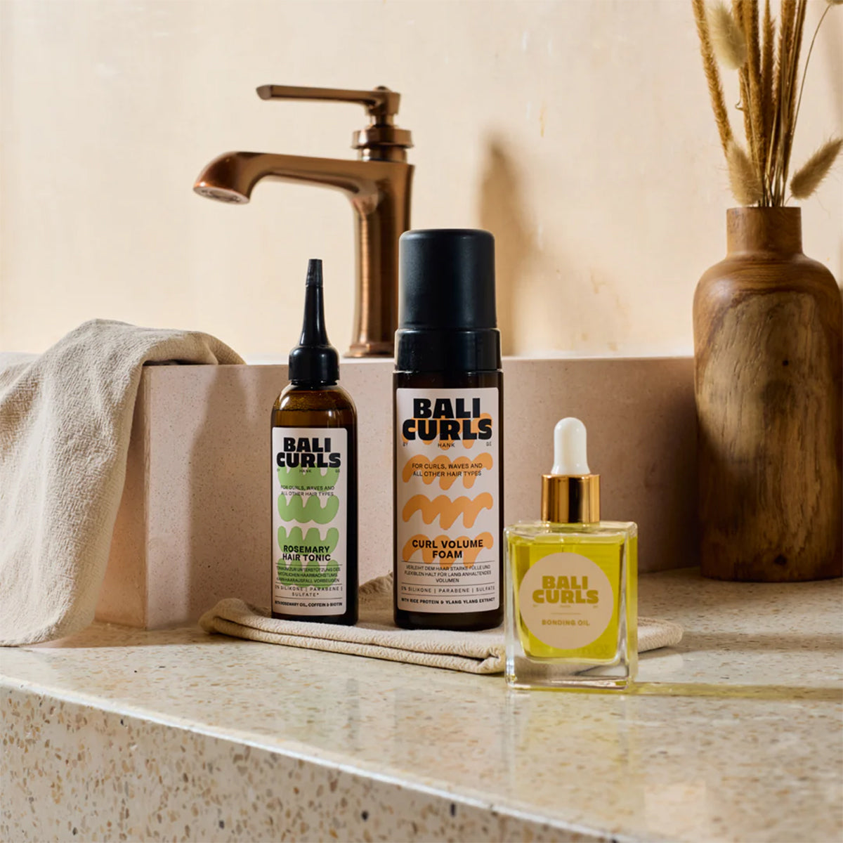 BALI CURLS-Produkte auf dem Badezimmertisch – Rosemary Hair Tonic, Curl Volume Foam** und Bonding O bei natürlichem Licht.