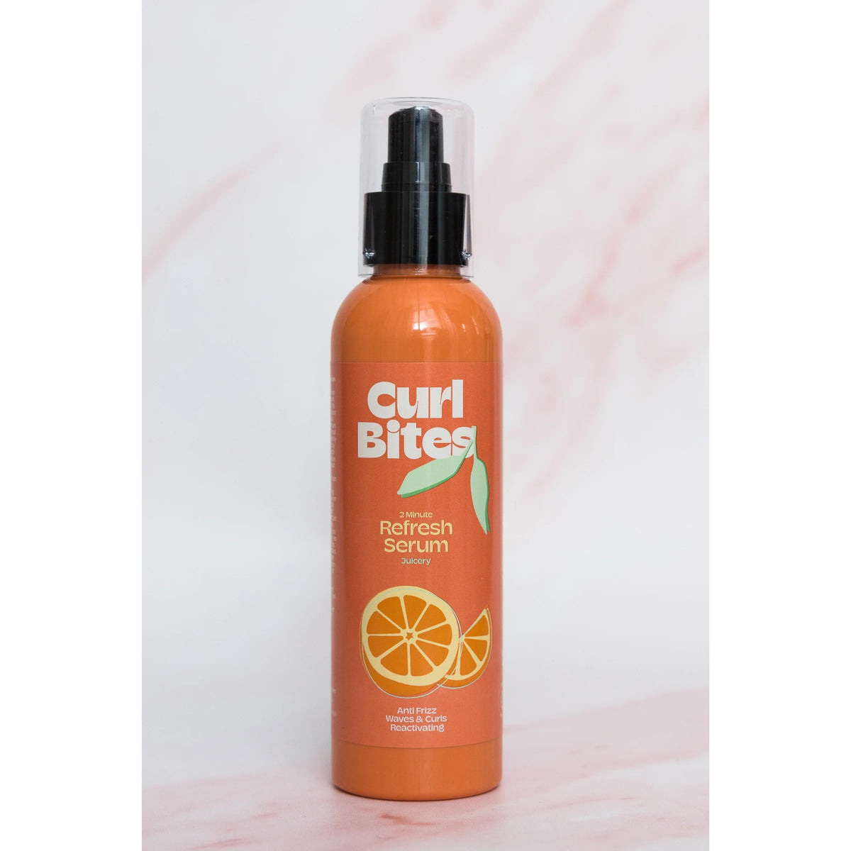 Curl Bites 2 Minute Refresh Serum, orangefarbene Flasche mit schwarzer Pumpe und orangefarbenem Motiv auf hellem Marmorhintergrund.
