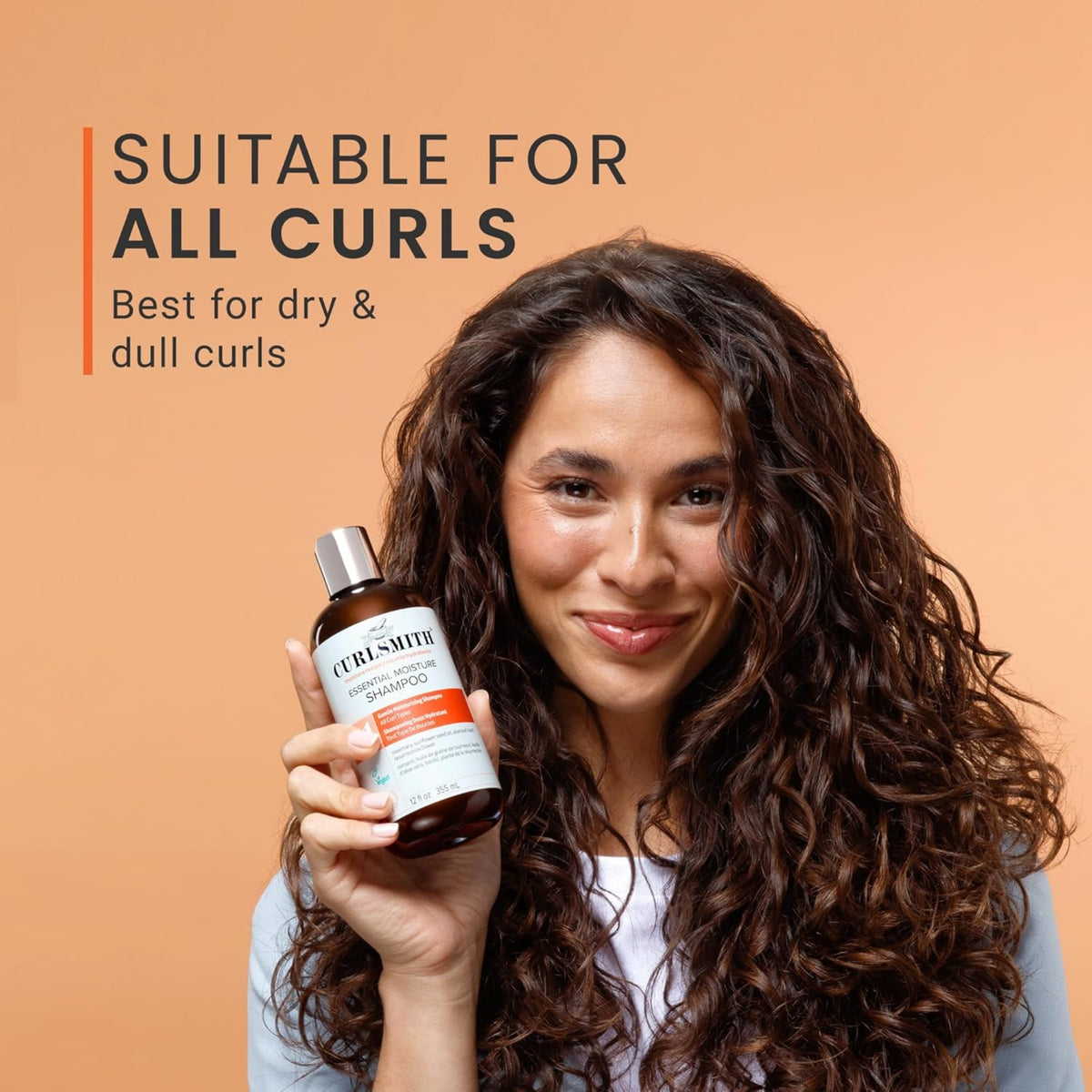 Frau mit lockigem Haar hält Curlsmith Essential Moisture Shampoo, geeignet für alle Locken, am besten für trockenes und stumpfes Haar.
