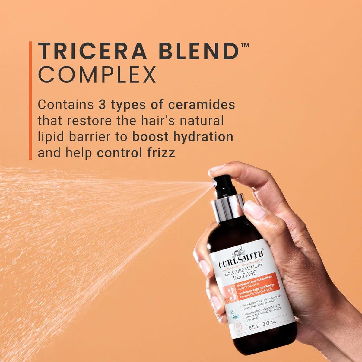 Handsprays Curlsmith Moisture Memory Release mit TriCera Blend Complex auf orangefarbenem Hintergrund.
