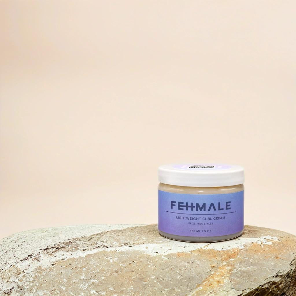 Fehmale Lightweight Curl Cream 150 ml in einem Behälter mit violettem Etikett, platziert auf Naturstein vor beigem Hintergrund.