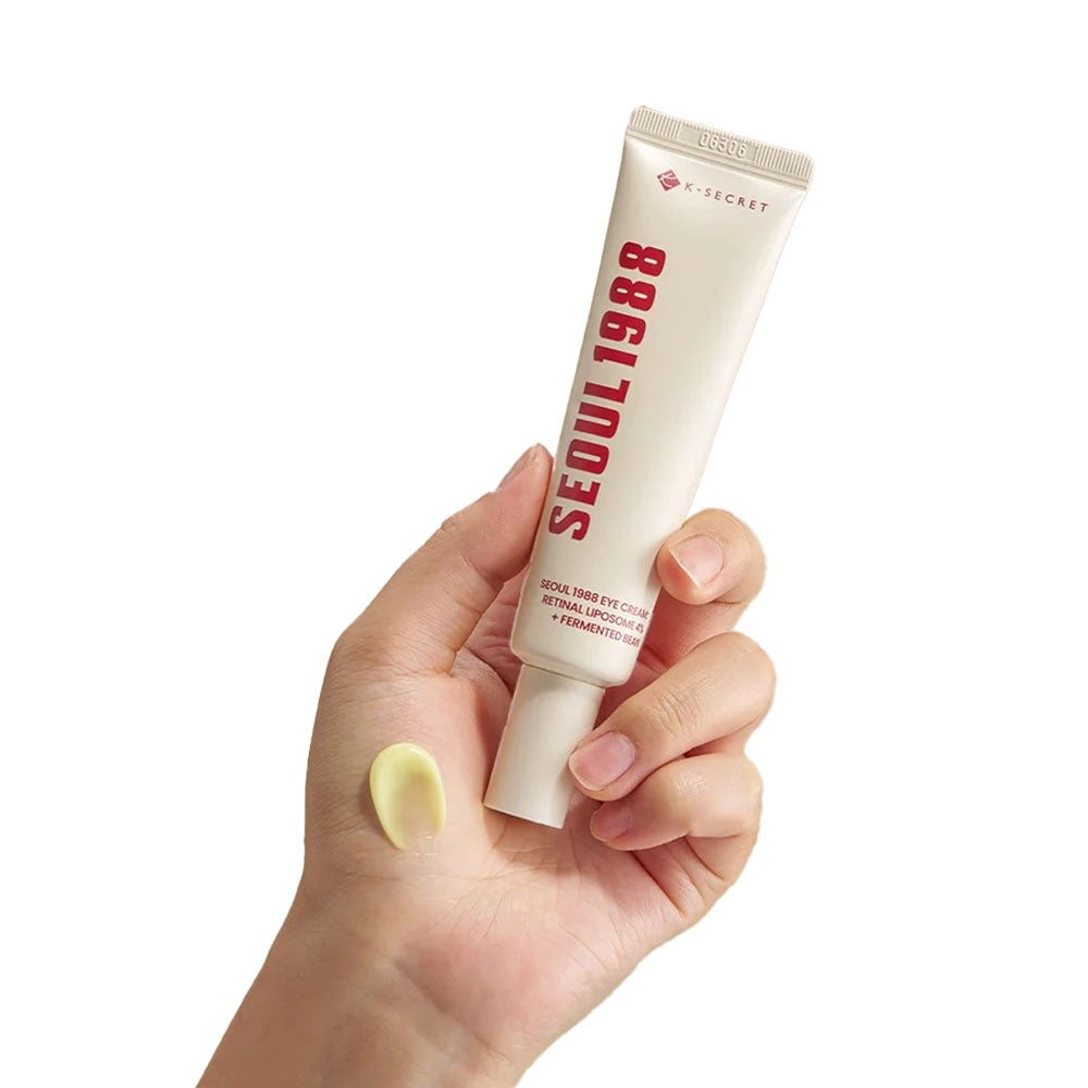 K-Secret Augencreme: Netzhautliposom 4 % + fermentierte Bohne 30 ml in der Hand gehalten mit gelber, cremiger Konsistenz auf der Haut.