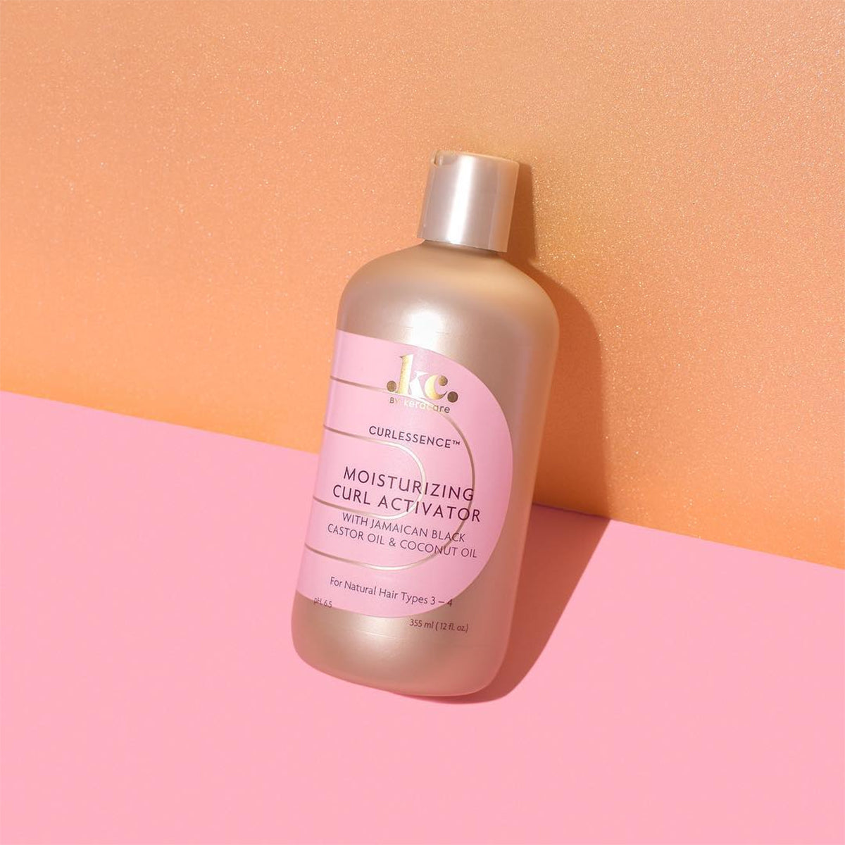 Keracare Curlessence Moisturizing Curl Activator für Naturhaartypen 3–4, 355-ml-Flasche mit goldenem Verschluss, fotografiert vor einem farbenfrohen Hintergrund.