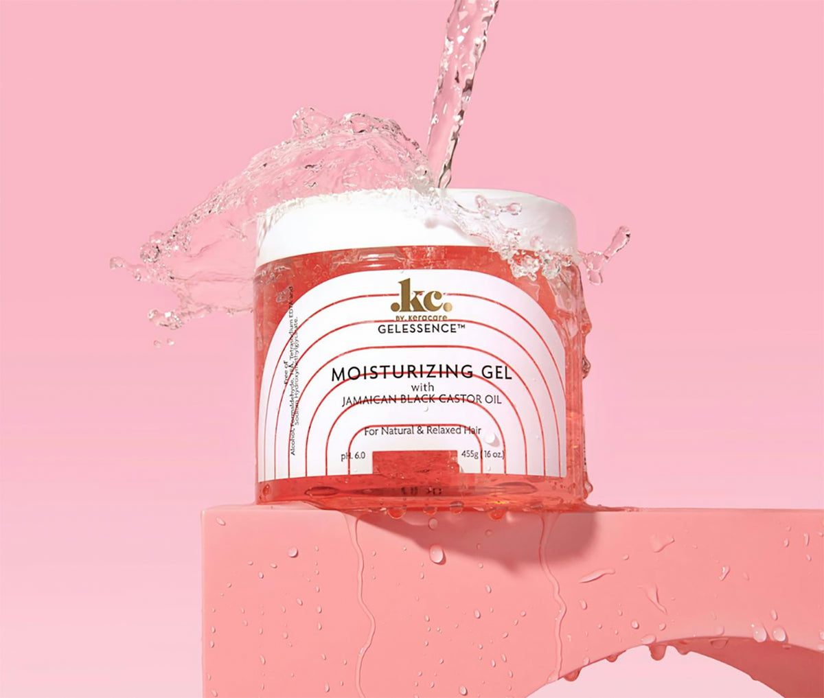 Durchsichtiger Behälter mit KeraCare Gelessence Feuchtigkeitsgel. Wasser spritzt rund um den Behälter auf rosa Hintergrund und unterstreicht die feuchtigkeitsspendenden Eigenschaften des Produkts.
