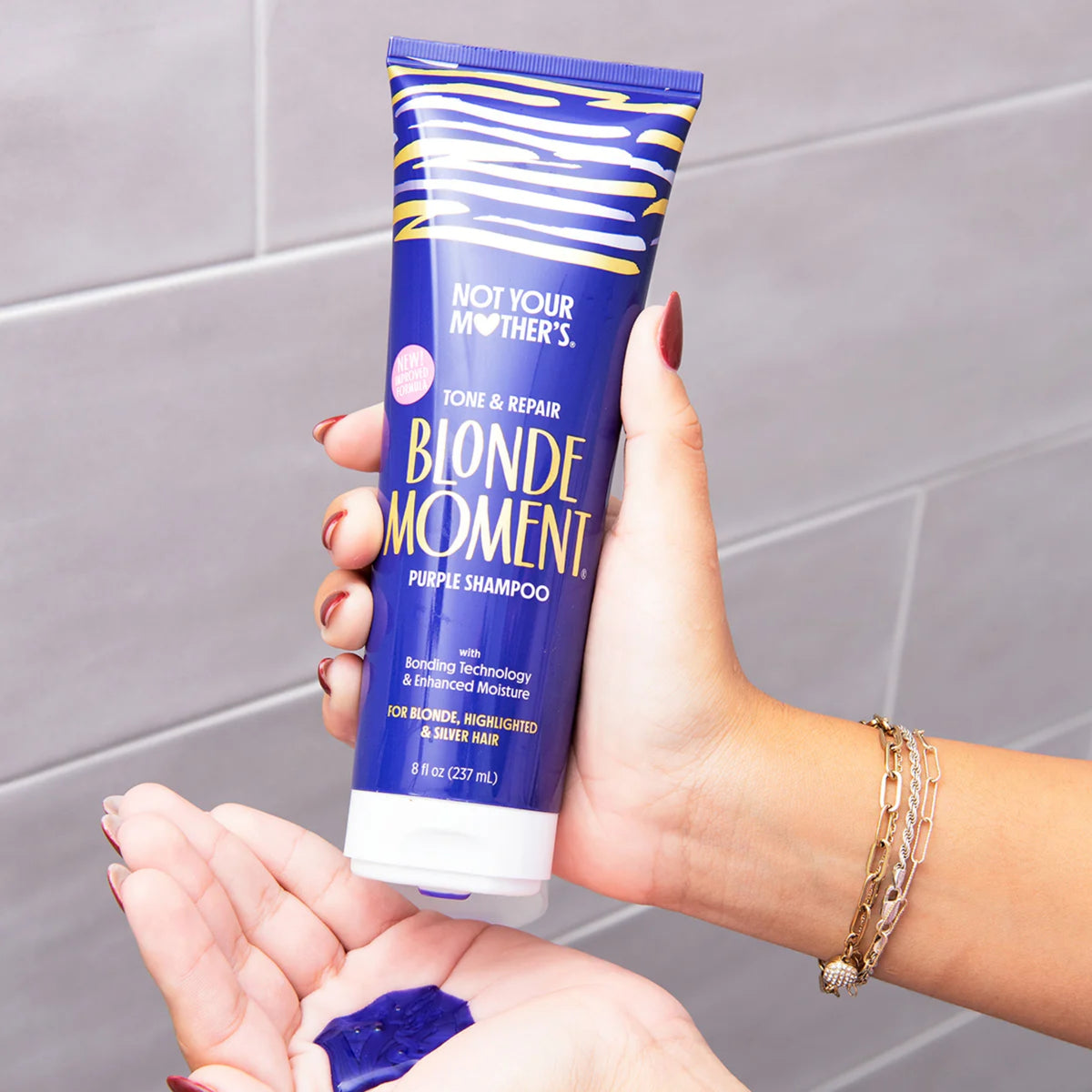 Nicht das lilafarbene Shampoo „Not Your Mother's Blonde Moment“ in der Hand und das violette Produkt in der Handfläche.