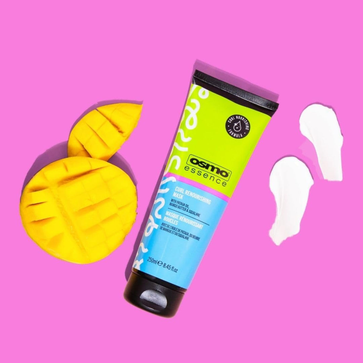 OSMO Essence Curl Renourishing Mask Tube auf rosa Hintergrund mit geschnittener Mango und cremigen Texturstrichen.
