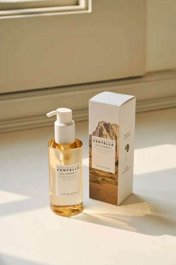 Flasche SKIN1004 Madagascar Centella Light Cleansing Oil 200 ml neben einer ästhetischen Verpackung im Sonnenlicht auf der Fensterbank.