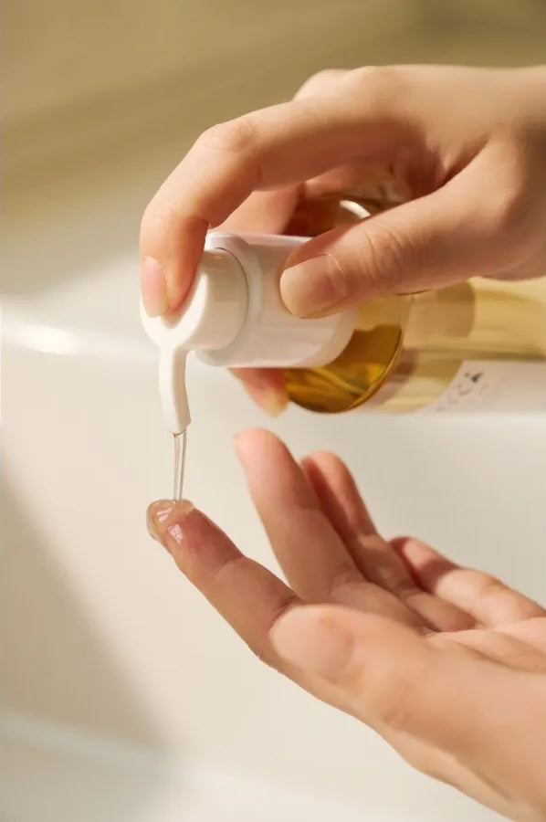 Dosiert das SKIN1004 Madagascar Centella Light Cleansing Oil 200 ml per Hand mit einer Pumpe über dem Waschbecken in sanftem, warmem Licht.