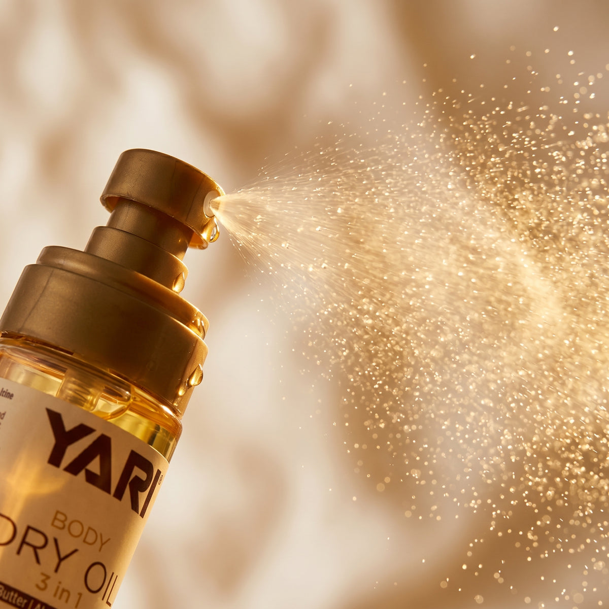 Yari Body Dry Oil 3 in 1 in einer goldenen Flasche, die einen feinen Nebel Körperöl versprüht.